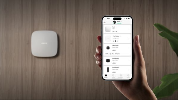 Une personne tient un téléphone portable devant un système de sécurité.