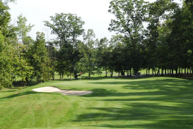 A golf course with trees and a bunker in the middle