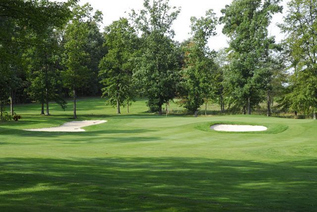 A golf course with trees and a sand trap in the middle of it