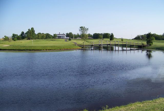 A bridge over a body of water with a golf course in the background