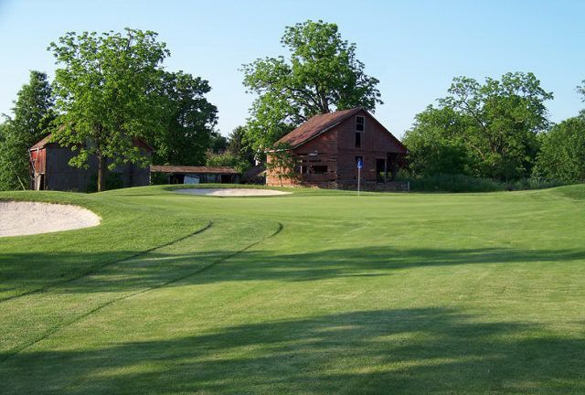 A golf course with a barn in the background