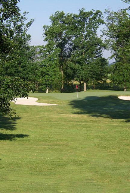 A golf course with trees and bunkers in the background