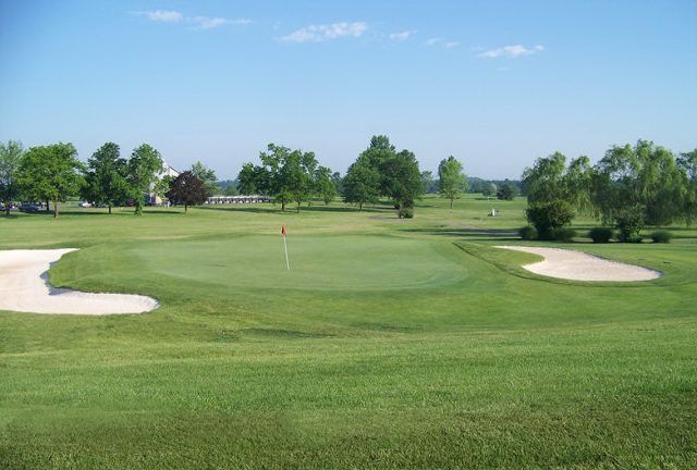 A golf course with a green and bunkers on a sunny day.
