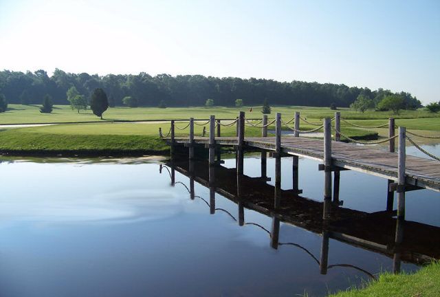 A bridge over a body of water with a golf course in the background