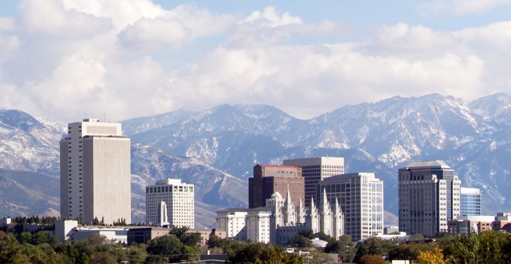 A city skyline with mountains in the background on a sunny day.