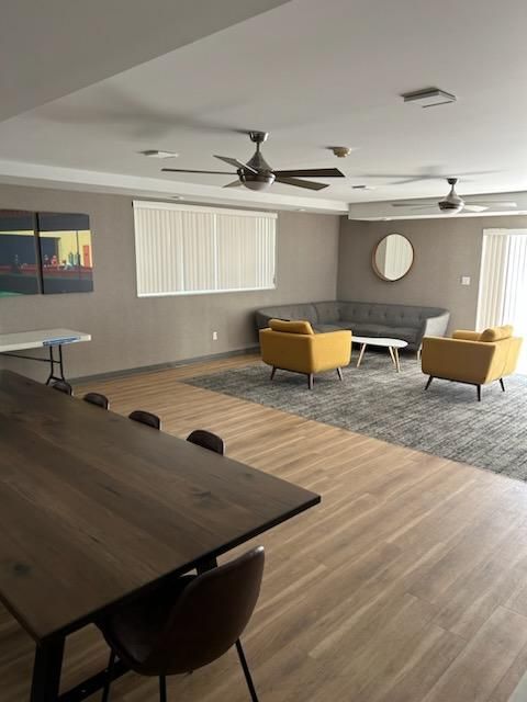 A living room with a table , chairs , a couch and a ceiling fan.