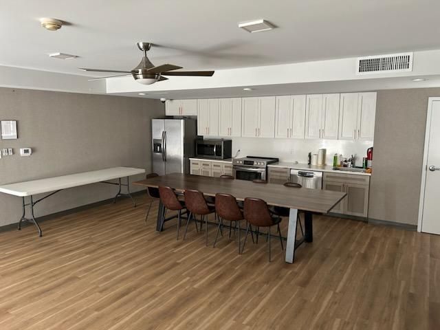 A kitchen with a table and chairs and a ceiling fan.