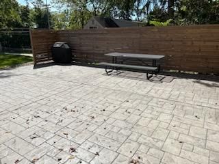 A picnic table is sitting on a patio next to a wooden fence.