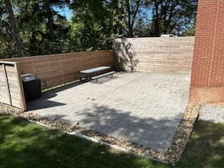 A patio with a wooden fence and a picnic table.