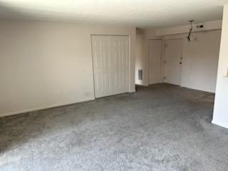 An empty living room with a gray carpet and white walls.