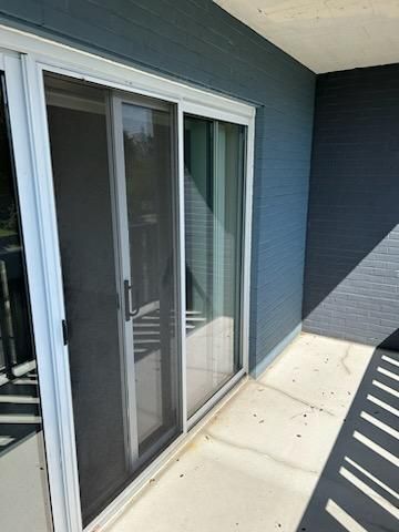 A sliding glass door with a screen on it is on a balcony.