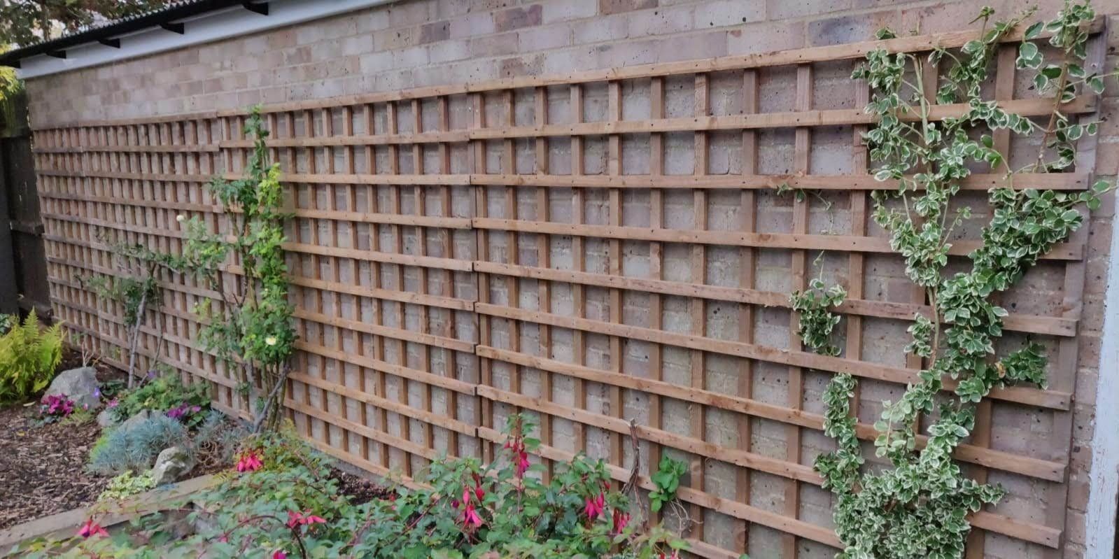 A trellis covering all of a brick wall for plants to grow up.