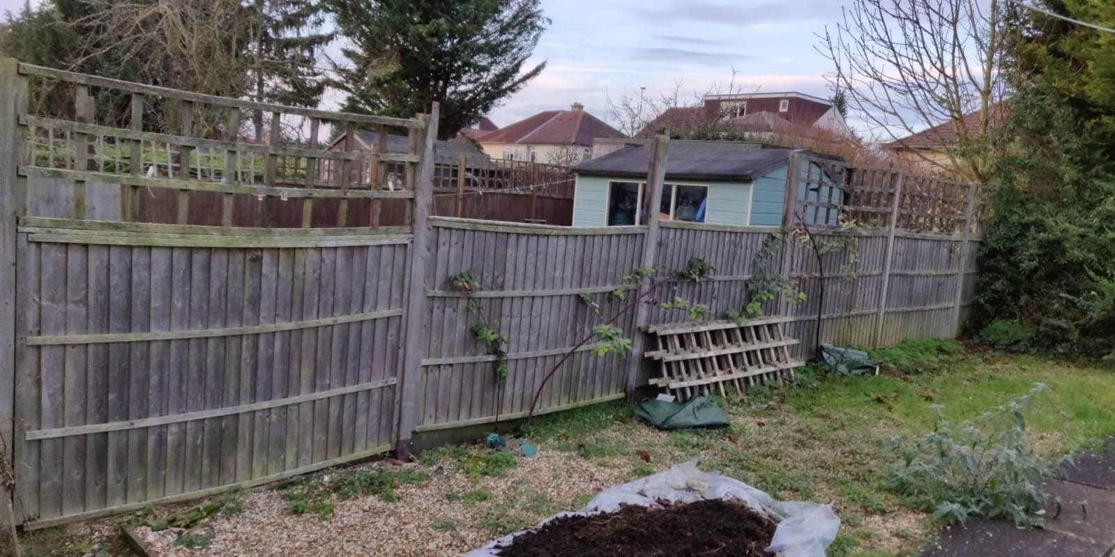 old wooden fence with trellis top before being replaced.