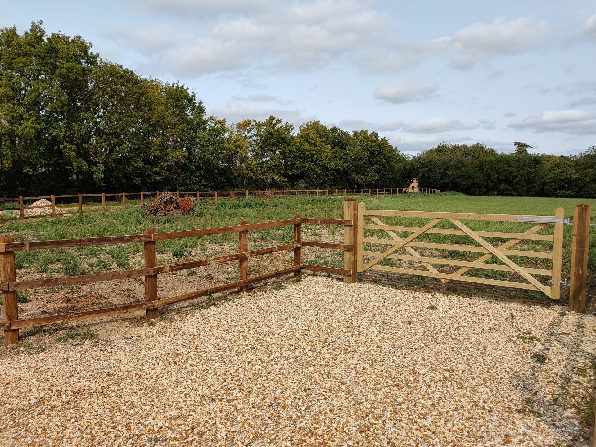 A wide wooden field gate allows access by vehicles. Blends in with wooden fence.