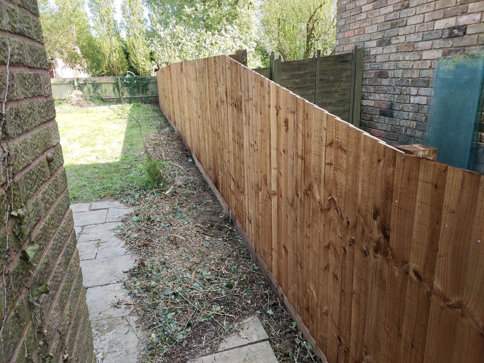 Inclined feather edge fence going whole length of house from high at the back sloping to low at the front.