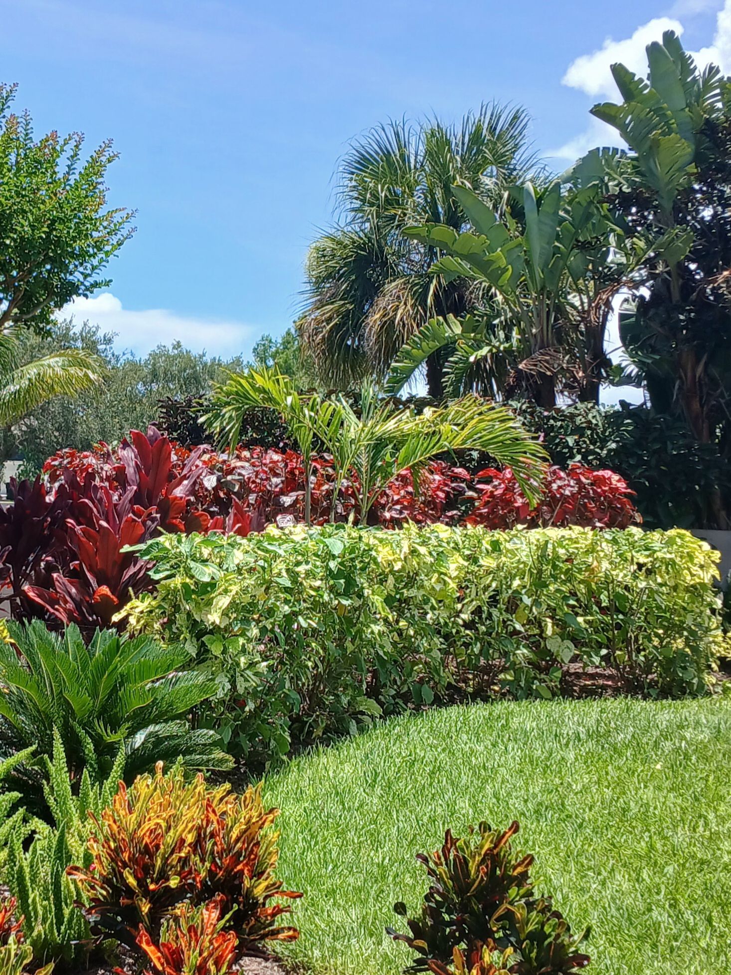 Stone path leads to a house with cream-colored siding and green shutters, a decorative metal panel in the garden.