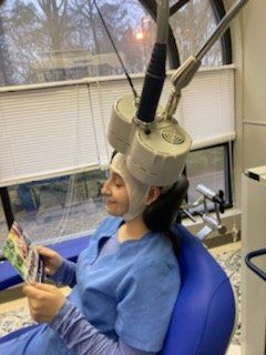A woman is sitting in a chair with a device on her head