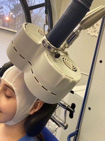 A person with a bandage on their head is getting a treatment from a machine