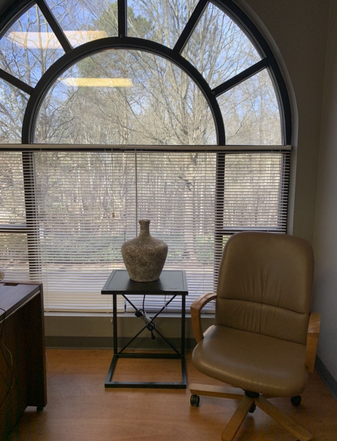 A chair is sitting in front of a large window with blinds.