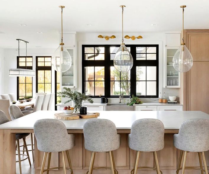 Dining room windows overlooking a lush green garden, with a dark table and candle centerpiece