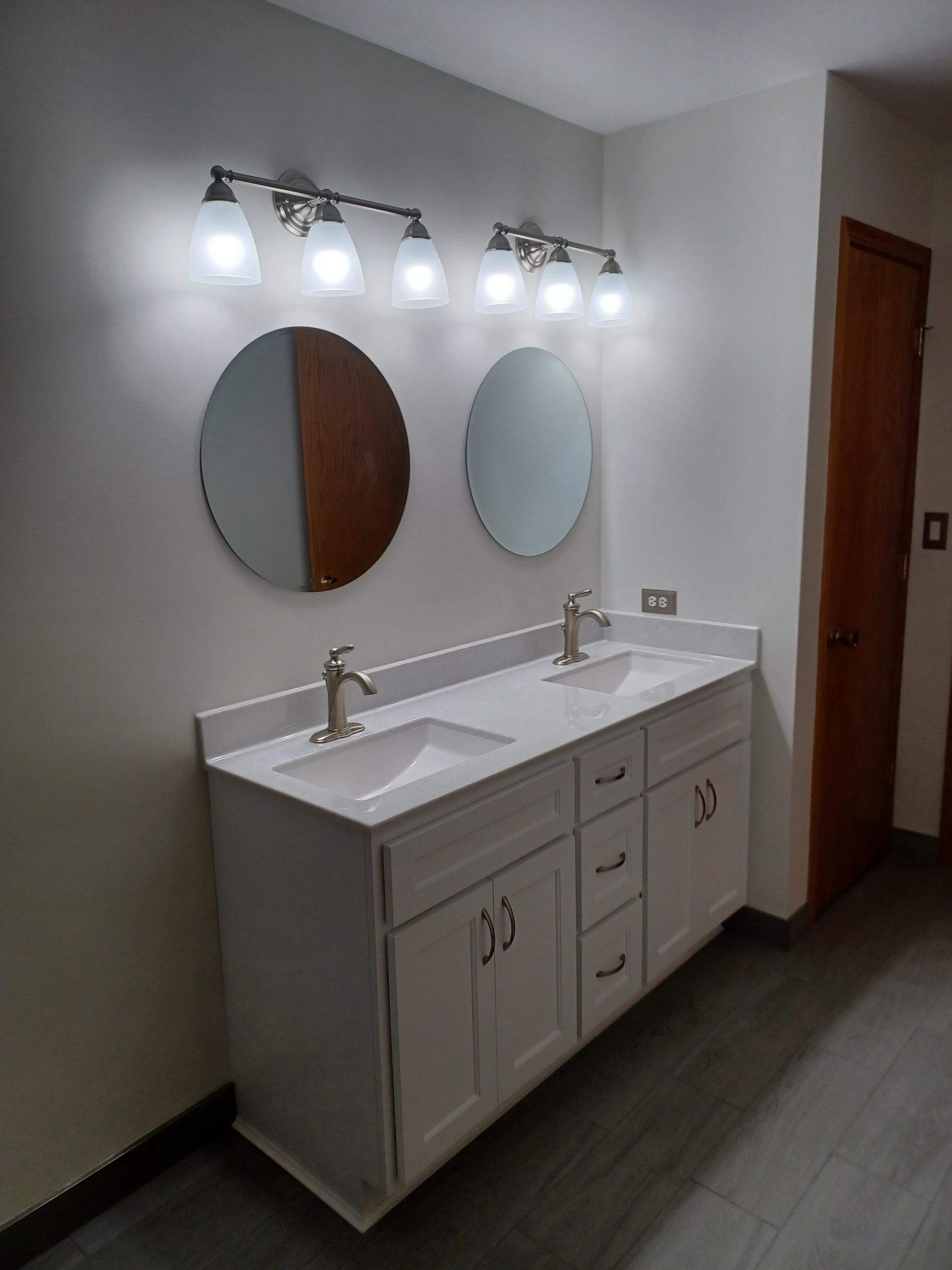 Bathroom with white double vanity, round mirrors, and brushed nickel fixtures.