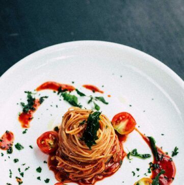 a white plate topped with spaghetti and tomatoes on a table .