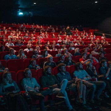 a large group of people are sitting in a theater watching a movie .