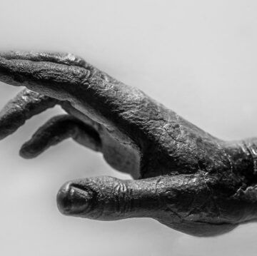 a black and white photo of a statue of a hand reaching out .