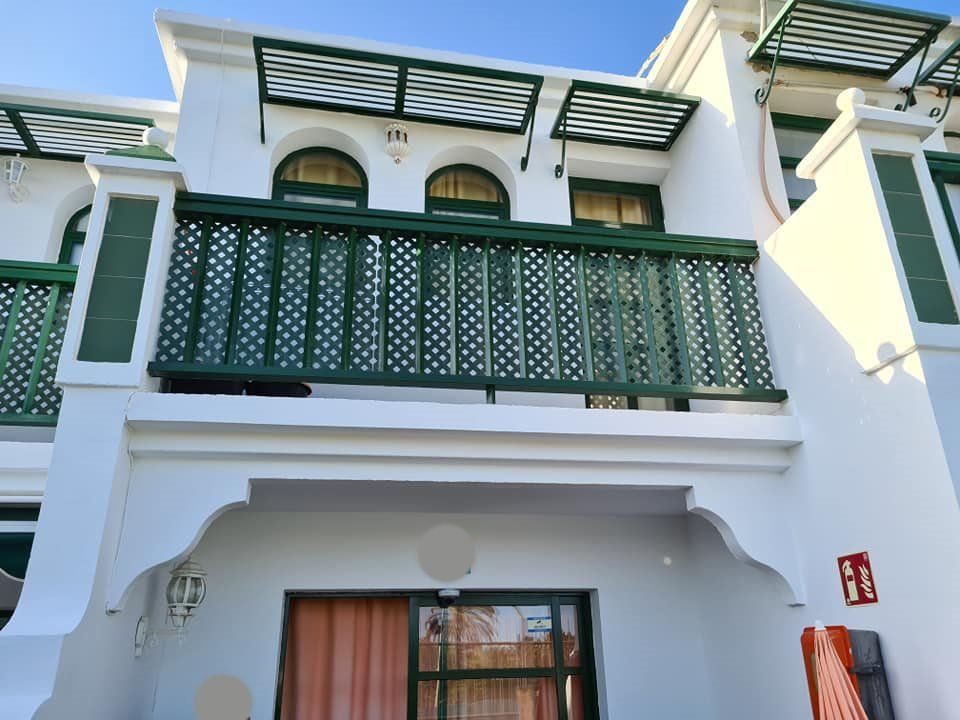 Ein weißes Gebäude mit grünen Balkonen und Fensterläden