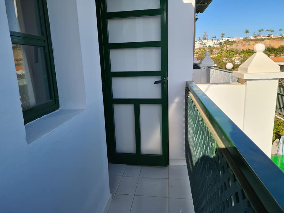 Ein Balkon mit einer grünen Tür und einem Fenster