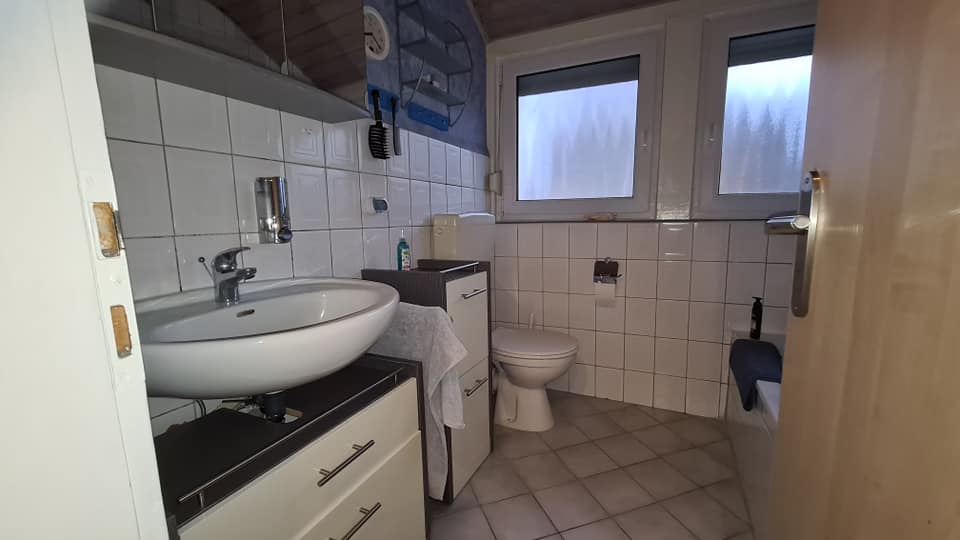 Ein Badezimmer mit Waschbecken, Toilette und Fenster.
