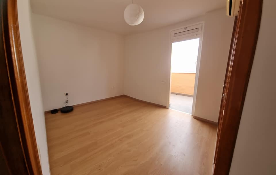Ein leerer Raum mit Hartholzböden und einer Tür, die auf einen Balkon führt.