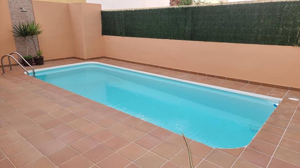 Im Hinterhof eines Hauses befindet sich ein großer Swimmingpool.