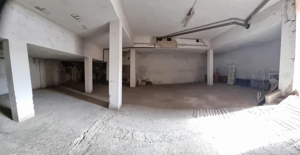 Eine große leere Lagerhalle mit Säulen und einem Garagentor.