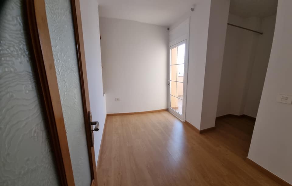 Ein leerer Raum mit Holzboden und Glastür.