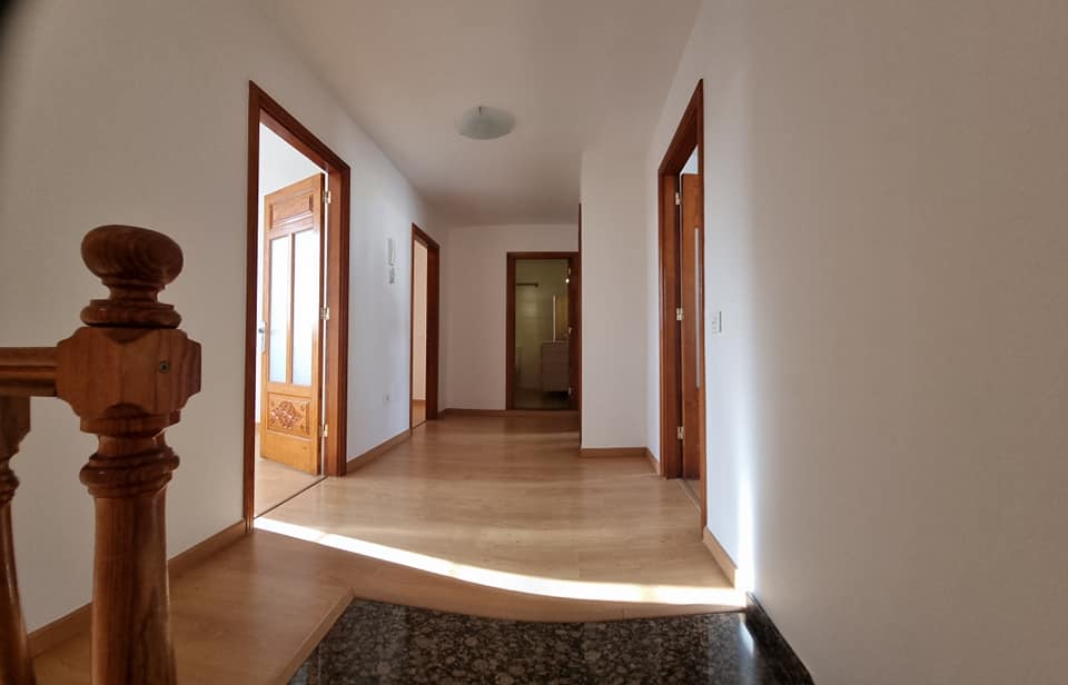 Ein langer Flur mit einem Holzgeländer und Treppen in einem Haus.