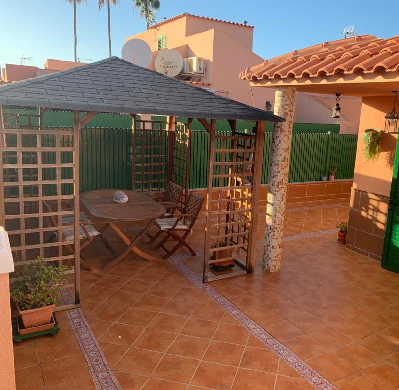 Eine Terrasse mit Tisch und Stühlen unter einem Pavillon