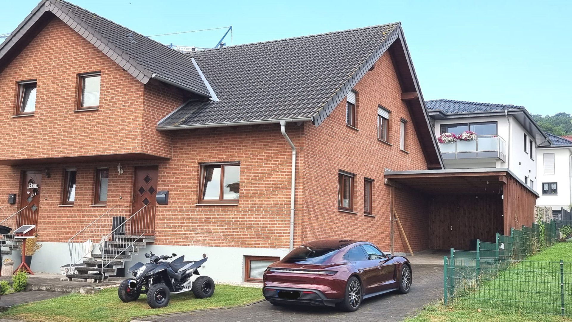 Ein rotes Auto steht vor einem Backsteinhaus