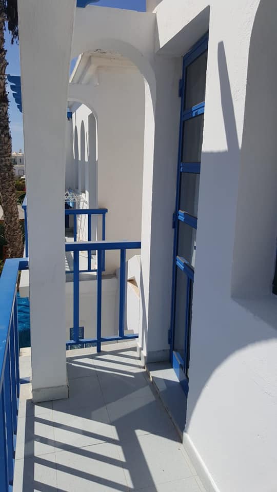 Ein weißes Gebäude mit einer blauen Tür und einem blauen Geländer.