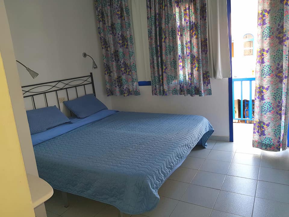 Ein Schlafzimmer mit einem blauen Bett und geblümten Vorhängen