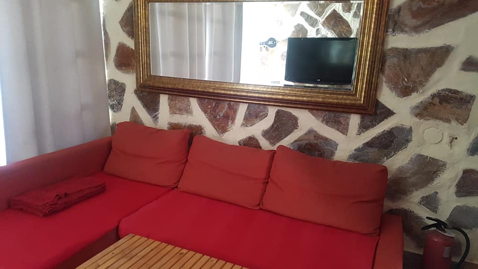 Ein Wohnzimmer mit einer roten Couch, einem Tisch und einem Fernseher.