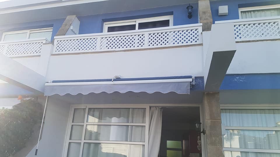 Ein blau-weißes Haus mit einer weißen Markise auf dem Balkon.
