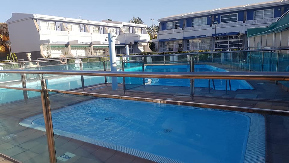 Ein großer Swimmingpool ist von einem Glaszaun umgeben.