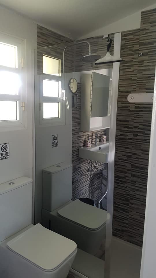 Ein Badezimmer mit Toilette, Waschbecken, Spiegel und Dusche.