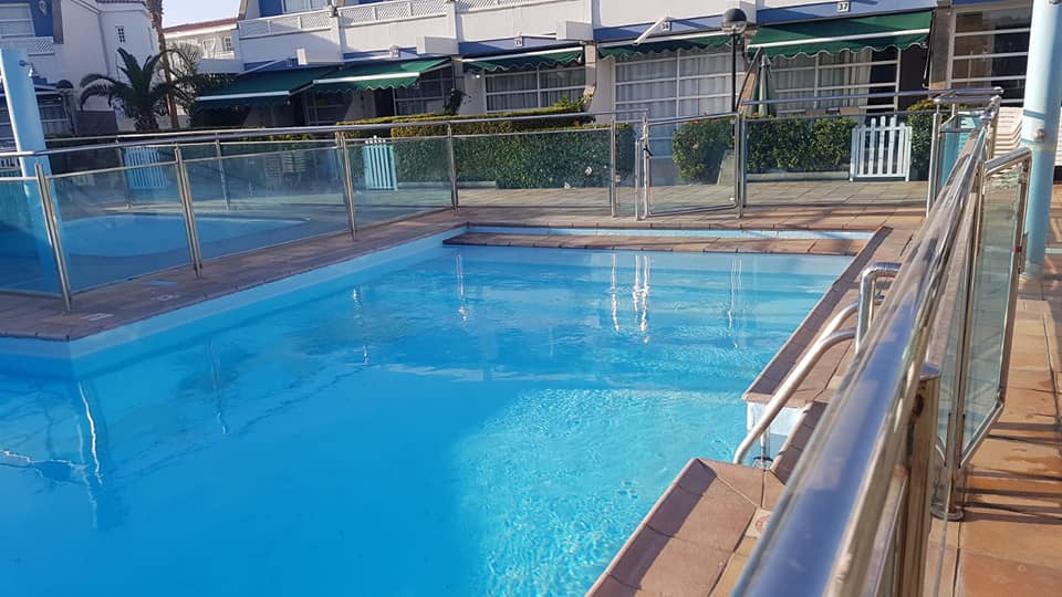 Ein großer Swimmingpool, umgeben von einem Glaszaun.