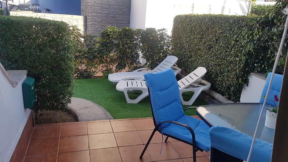 Eine Terrasse mit Tisch, Stühlen und einer Schaukel.