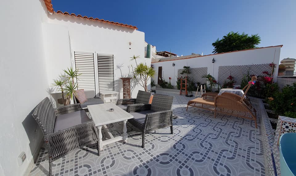 Eine Terrasse mit Tisch und Stühlen neben einem Pool.