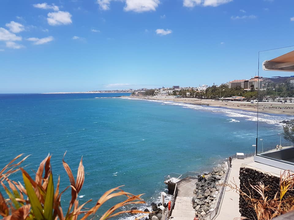 Ein Blick auf einen Strand von einem Balkon mit Blick auf das Meer.