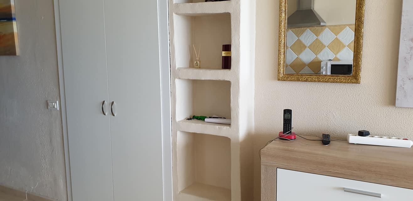 Ein Wohnzimmer mit Kommode, Regalen und Spiegel.