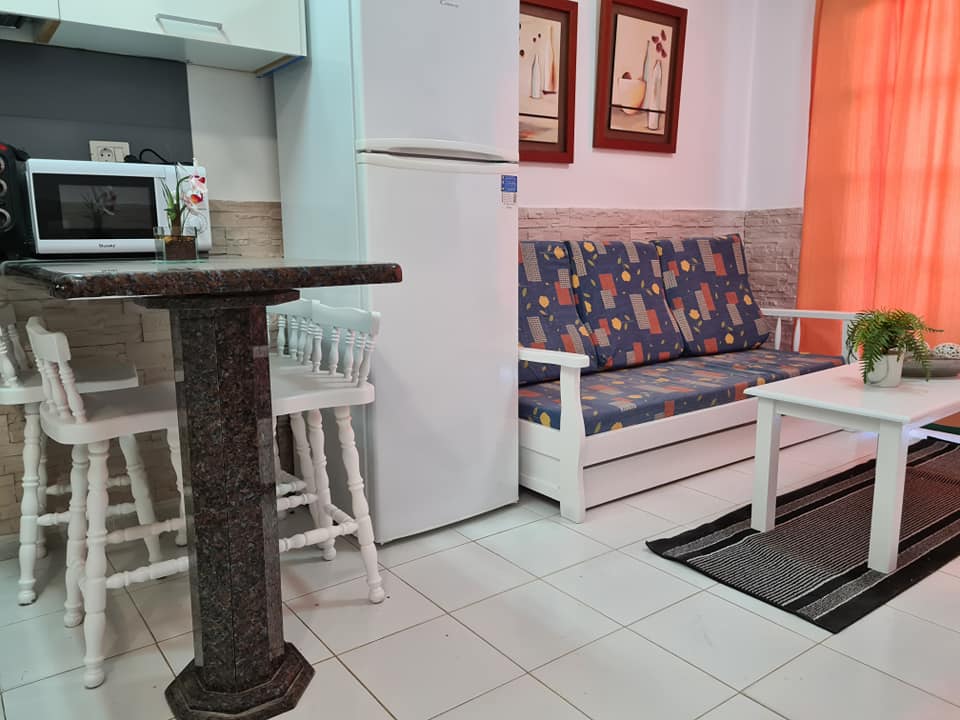 Ein Wohnzimmer mit Couch, Tisch, Stühlen und Kühlschrank.